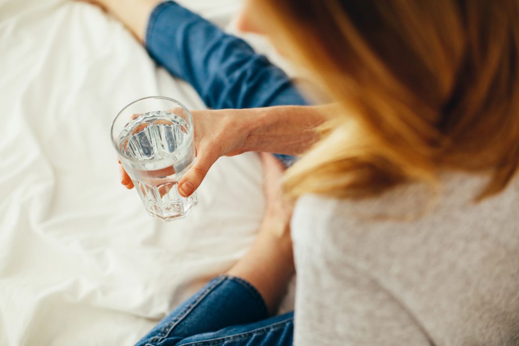 woman sitting on bed drinking water