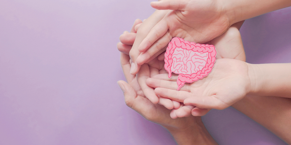 Cupped hands holding a pink paper intestine cutout.