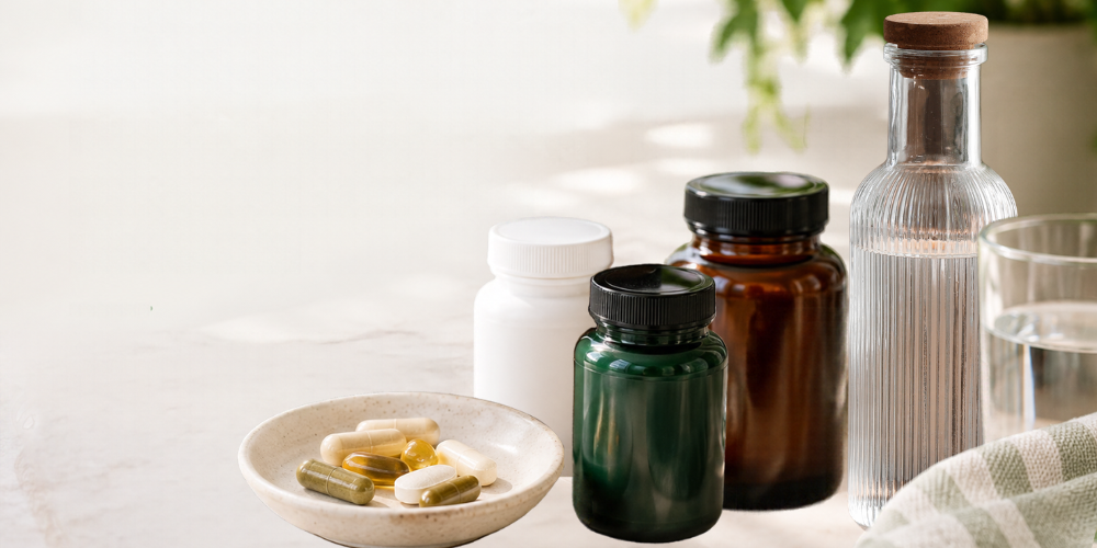 Supplements in various bottles with capsules displayed on a plate beside a glass of water.